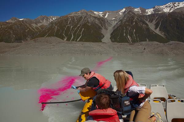 Fine arts student Amelia Hitchcock uses a special rig to distribute dye into the lake from a Glacier Explorers boat.  
